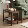 Walnut-finish solid rubberwood side table with lower shelf beside an olive green armchair
